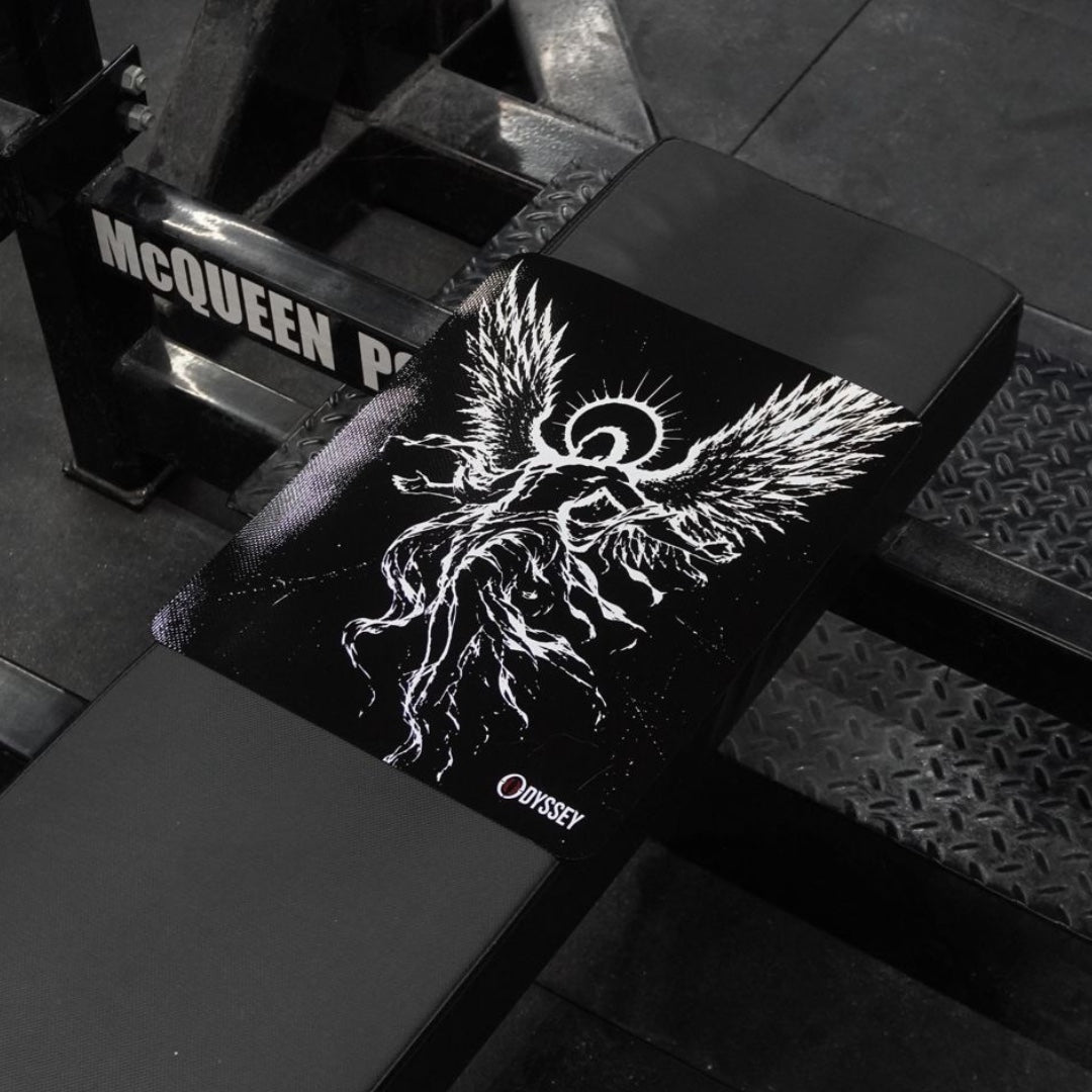 The Odyssey Icarus Bench Mat laid on a competition bench, white Icarus wings on the black mat